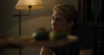 Movie still from “Operation Finale” (2018), directed by Chris Weitz – A man sitting in front of a table holding a plate of food; Close Up shot, Over the shoulder angle