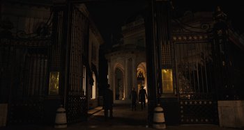 Movie still from “Operation Finale” (2018), directed by Chris Weitz – Two people are walking through an archway at night; Extreme Wide shot, Low angle
