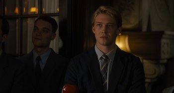 Movie still from “Operation Finale” (2018), directed by Chris Weitz – A man in a suit and tie standing next to another man in a suit and tie; Medium shot, Over the shoulder angle