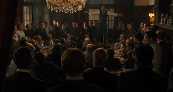 Movie still from “Operation Finale” (2018), directed by Chris Weitz – A group of people sitting around a table; Wide shot, Over the shoulder angle