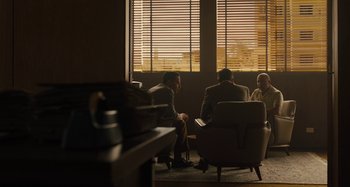 Movie still from “Operation Finale” (2018), directed by Chris Weitz – Three people are sitting in front of a large window; Wide shot, Over the shoulder angle