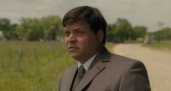 Movie still from “Operation Finale” (2018), directed by Chris Weitz – A person wearing a suit and tie; Close Up shot, Over the shoulder angle