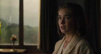Movie still from “Operation Finale” (2018), directed by Chris Weitz – A young woman in a white jacket looking out of a window; Close Up shot, Over the shoulder angle