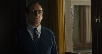 Movie still from “Operation Finale” (2018), directed by Chris Weitz – An older man wearing glasses and a sweater; Medium shot, Low angle