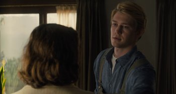 Movie still from “Operation Finale” (2018), directed by Chris Weitz – A young man standing in front of a woman in front of a window; Medium shot, Over the shoulder angle