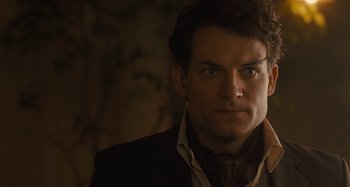 Movie still from “Operation Finale” (2018), directed by Chris Weitz – A person wearing a suit and tie; Close Up shot, Over the shoulder angle