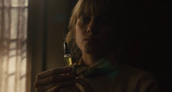 Movie still from “Operation Finale” (2018), directed by Chris Weitz – A woman holding a small bottle with a needle in it; Close Up shot, Low angle