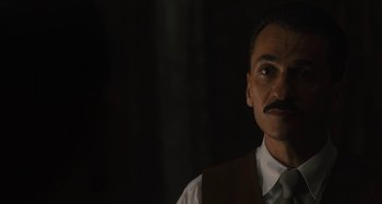 Movie still from “Operation Finale” (2018), directed by Chris Weitz – A man with a mustache wearing a white shirt and a vest; Close Up shot, Low angle