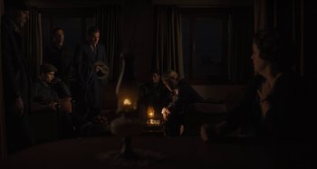 Movie still from “Operation Finale” (2018), directed by Chris Weitz – A group of people sitting around a living room with lit candles; Wide shot, High angle