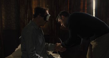 Movie still from “Operation Finale” (2018), directed by Chris Weitz – Two men are holding hands while one is wearing a blindfold; Medium shot, Over the shoulder angle