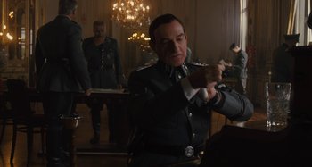 Movie still from “Operation Finale” (2018), directed by Chris Weitz – A man in a military uniform is holding a sword; Medium shot, Over the shoulder angle