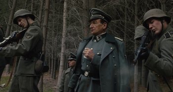 Movie still from “Operation Finale” (2018), directed by Chris Weitz – Two men in military uniforms standing next to each other in the woods; Medium shot, Low angle