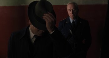 Movie still from “Operation Finale” (2018), directed by Chris Weitz – A man in a suit and tie and a man in a hat; Close Up shot, Over the shoulder angle