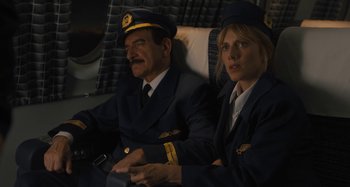 Movie still from “Operation Finale” (2018), directed by Chris Weitz – A man and a woman sitting next to each other on a plane; Medium shot, High angle