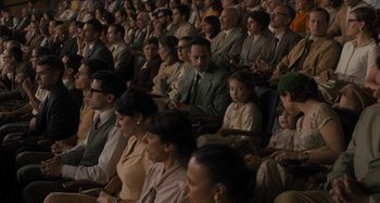 Movie still from “Operation Finale” (2018), directed by Chris Weitz – A group of people sitting in a room watching a show; Wide shot, High angle