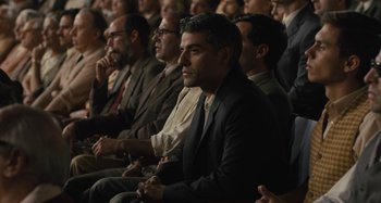 Movie still from “Operation Finale” (2018), directed by Chris Weitz – A group of people sitting in a row of seats; Medium shot, Over the shoulder angle