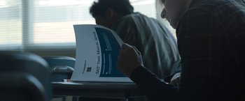 Movie still from “Operation Varsity Blues” (2021), directed by Chris Smith – A person sitting at a table reading a book; Extreme Close Up shot, Over the shoulder angle