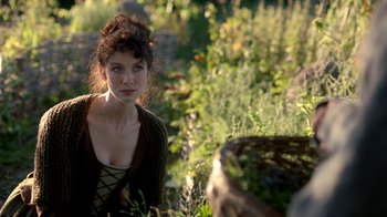 Movie still from “Outlander” (2014), created by Ronald D. Moore – A beautiful young woman standing in a field; Close Up shot, Over the shoulder angle