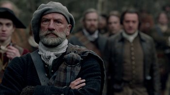 Movie still from “Outlander” (2014), created by Ronald D. Moore – A group of men standing next to each other; Medium shot, Low angle
