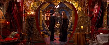Movie still from “Moulin Rouge!” (2001), directed by Baz Luhrmann – A man and a woman standing next to each other in front of a heart shaped mirror; Wide shot, High angle