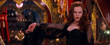 Movie still from “Moulin Rouge!” (2001), directed by Baz Luhrmann – A woman in a black dress is posing for a picture; Medium shot, Over the shoulder angle
