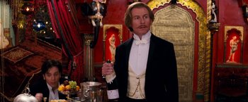 Movie still from “Moulin Rouge!” (2001), directed by Baz Luhrmann – A man in a tuxedo holding a bottle of wine; Medium shot, Low angle