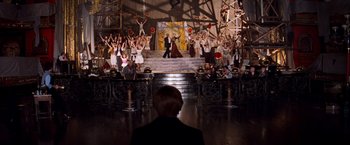 Movie still from “Moulin Rouge!” (2001), directed by Baz Luhrmann – A group of people standing in front of a stage; Wide shot, High angle