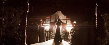 Movie still from “Moulin Rouge!” (2001), directed by Baz Luhrmann – A woman in a long black dress standing in front of a group of people; Wide shot, Low angle