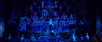 Movie still from “Moulin Rouge!” (2001), directed by Baz Luhrmann – A group of people standing on top of a stage; Extreme Wide shot, High angle