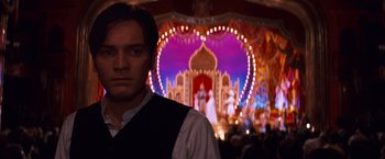 Movie still from “Moulin Rouge!” (2001), directed by Baz Luhrmann – A man standing in front of an illuminated heart; Medium shot, Over the shoulder angle