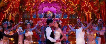 Movie still from “Moulin Rouge!” (2001), directed by Baz Luhrmann – A man and a woman are kissing in front of a group of dancers; Wide shot, Low angle