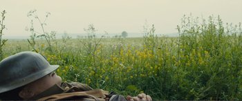 Movie still from “1917” (2019), directed by Sam Mendes – A field with yellow flowers in the background; Medium shot, Over the shoulder angle