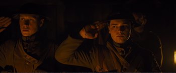 Movie still from “1917” (2019), directed by Sam Mendes – A man wearing a hat is holding his hand up to his ear; Close Up shot, Low angle