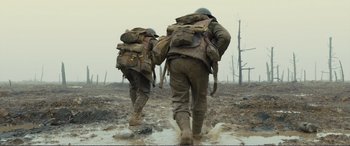 Movie still from “1917” (2019), directed by Sam Mendes – A couple of men walking across a muddy field; Medium shot, Low angle