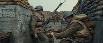 Movie still from “1917” (2019), directed by Sam Mendes – Two men dressed in military uniforms are holding a rifle; Medium shot, High angle