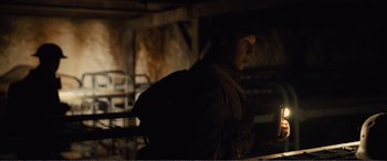 Movie still from “1917” (2019), directed by Sam Mendes – A man wearing a hat standing in a dark room; Medium shot, Low angle