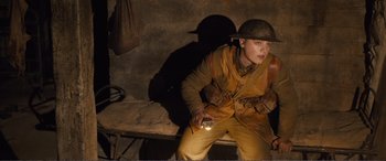 Movie still from “1917” (2019), directed by Sam Mendes – A man in a uniform holding something in his hand; Medium shot, High angle