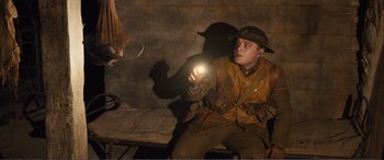 Movie still from “1917” (2019), directed by Sam Mendes – A man in a uniform holding a flashlight in the dark; Medium shot, High angle