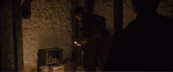 Movie still from “1917” (2019), directed by Sam Mendes – A man holding a flashlight while standing next to a wall; Medium shot, Over the shoulder angle