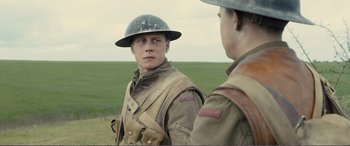 Movie still from “1917” (2019), directed by Sam Mendes – Two young men in military uniforms are standing in a field; Close Up shot, Over the shoulder angle