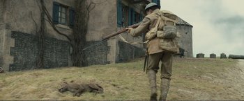 Movie still from “1917” (2019), directed by Sam Mendes – A man with a rifle in his hand is standing next to an animal; Wide shot, High angle