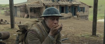 Movie still from “1917” (2019), directed by Sam Mendes – A man wearing a helmet is sitting in the dirt; Medium shot, Low angle
