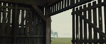 Movie still from “1917” (2019), directed by Sam Mendes – Smoke billows out of a field in the distance from a barn; Extreme Wide shot, Over the shoulder angle