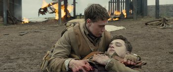 Movie still from “1917” (2019), directed by Sam Mendes – A man is holding a dead man in a field; Medium shot, Over the shoulder angle