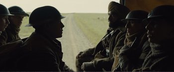 Movie still from “1917” (2019), directed by Sam Mendes – Two men are sitting in a vehicle on the side of the road; Medium shot, Over the shoulder angle