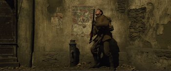 Movie still from “1917” (2019), directed by Sam Mendes – A man holding an umbrella in front of a fire hydrant; Wide shot, Low angle