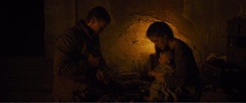 Movie still from “1917” (2019), directed by Sam Mendes – A man and a woman and a baby in a dark room; Medium shot, High angle