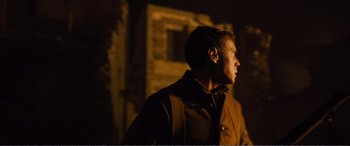 Movie still from “1917” (2019), directed by Sam Mendes – A man standing in the dark looking up at the sky; Medium shot, Over the shoulder angle