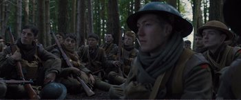 Movie still from “1917” (2019), directed by Sam Mendes – A group of men sitting on the ground in the woods; Medium shot, Low angle