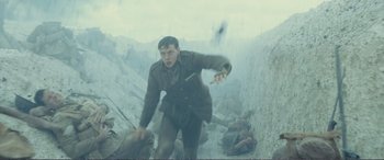 Movie still from “1917” (2019), directed by Sam Mendes – A man in a trench coat is running through the rubble; Medium shot, Low angle